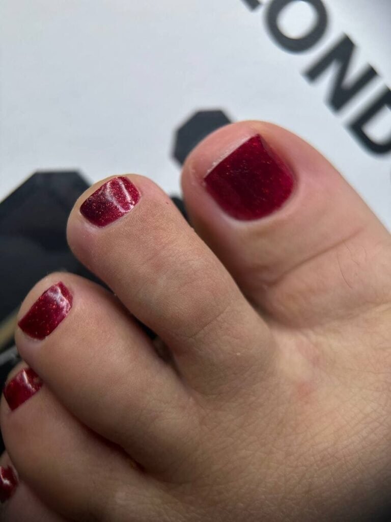 Ongles des pieds bordeaux avec finition scintillante